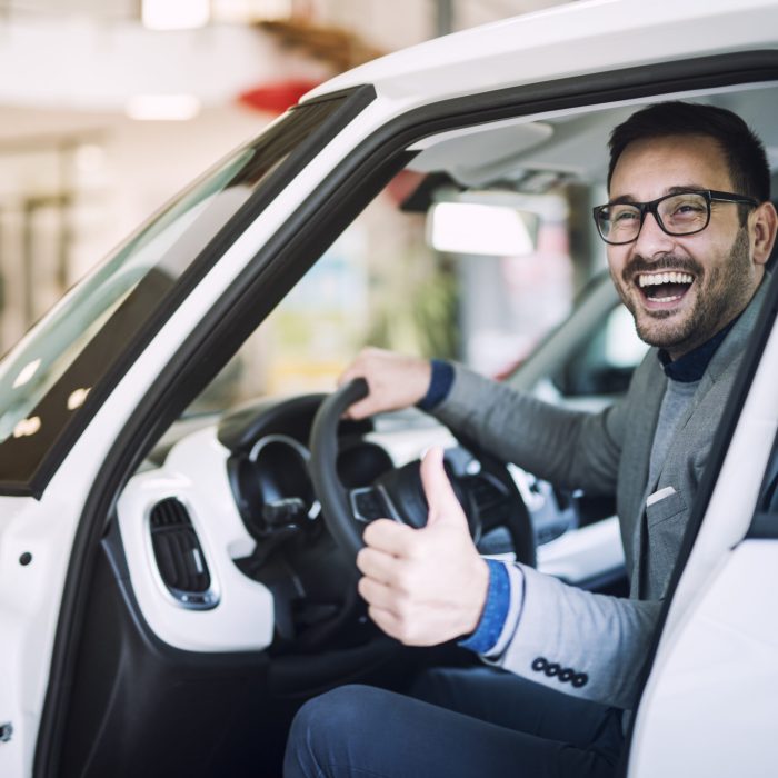 Happy satisfied customer just bought a brand new car at vehicle dealership.